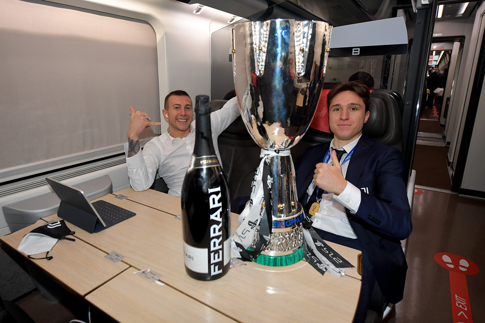 I calciatori della Juventus Federico Bernardeschi e Federico Chiesa a bordo del Frecciarossa con il trofeo della Supercoppa Italiana