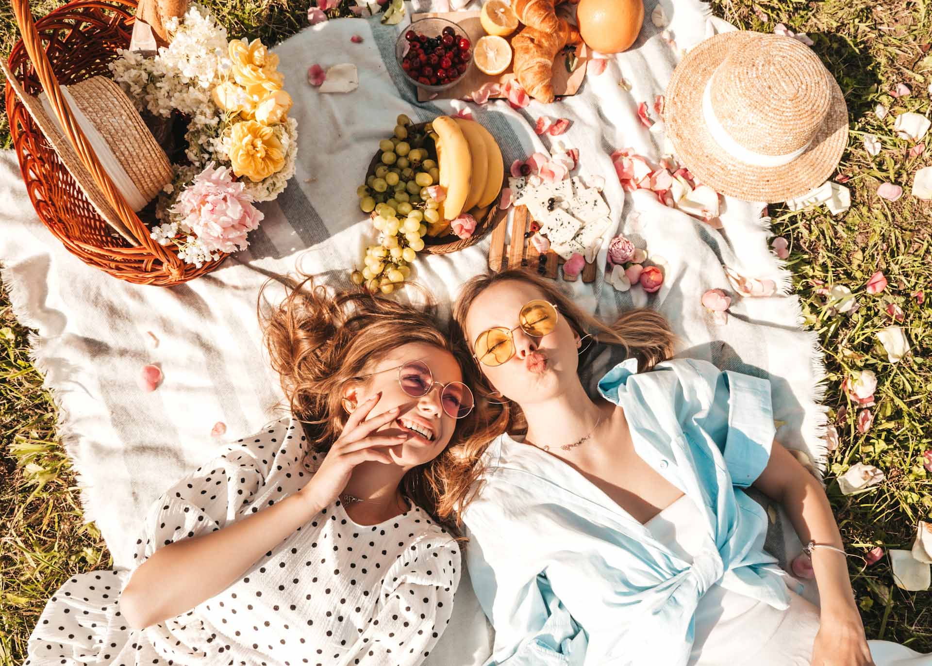 Due ragazze fanno un picnic con un cesto di frutta e un vassoio con croissant