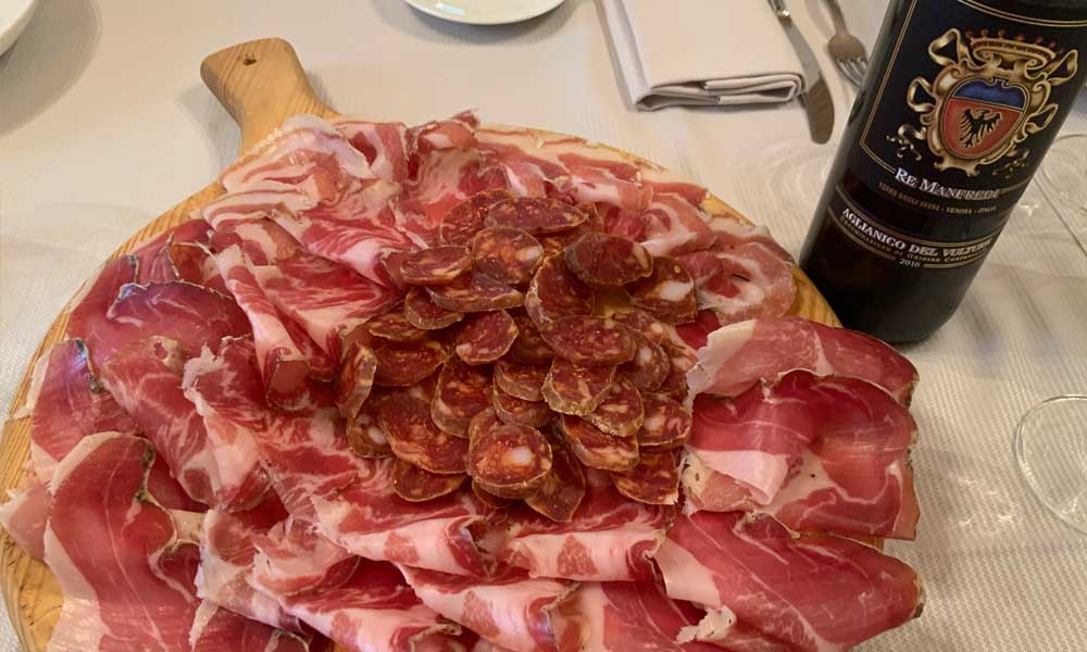 Piatto di salumi con bottiglia di vino Aglianico di Re Manfredi