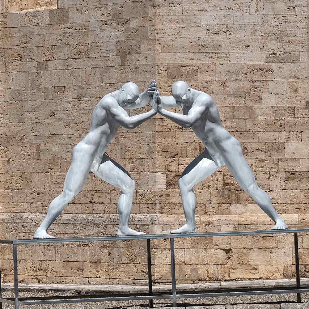 scultura raffigurante due uomini che si spingono a vicenda con le mani 