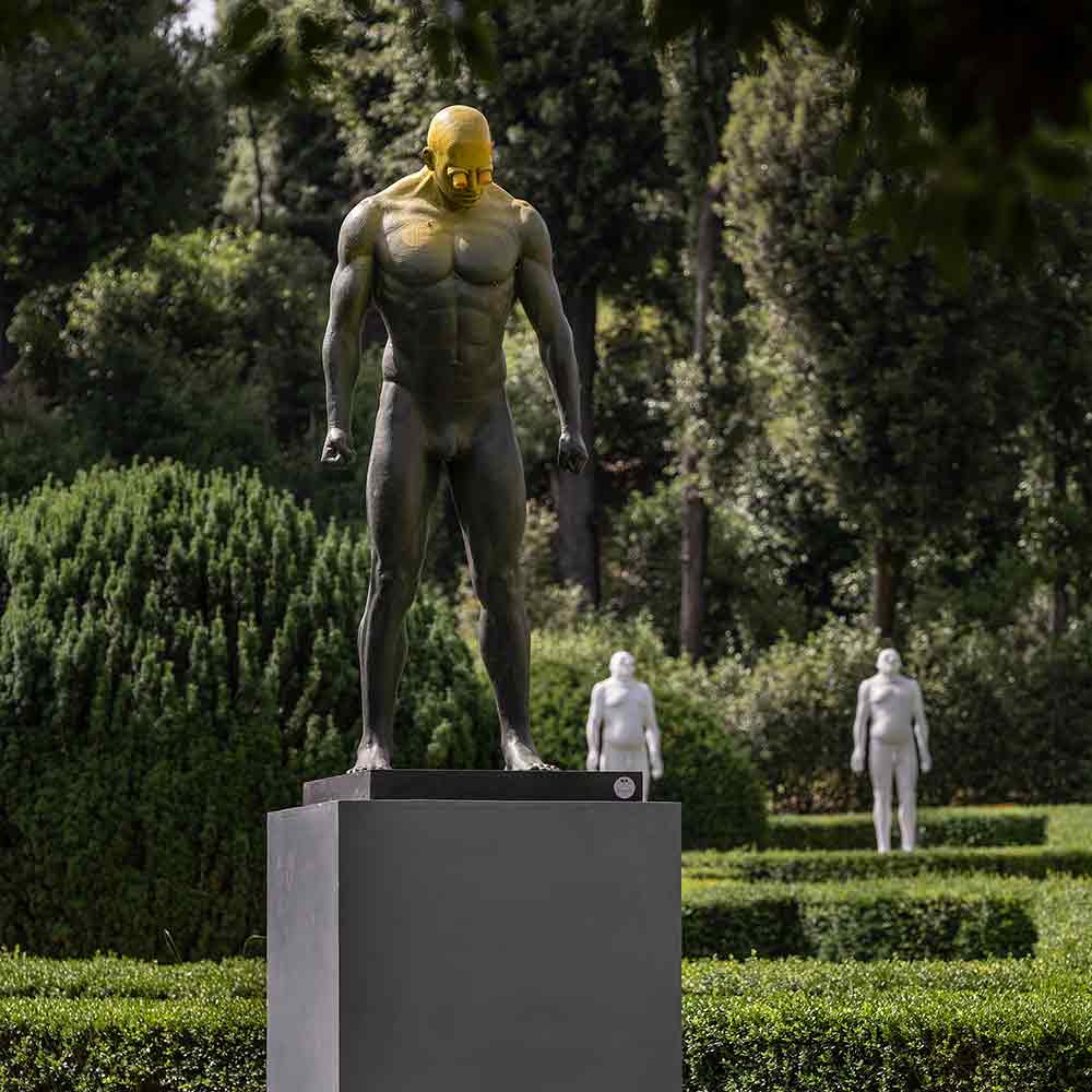 scultura di uomo in piedi con i pugni chiusi verso e le braccia verso il basso