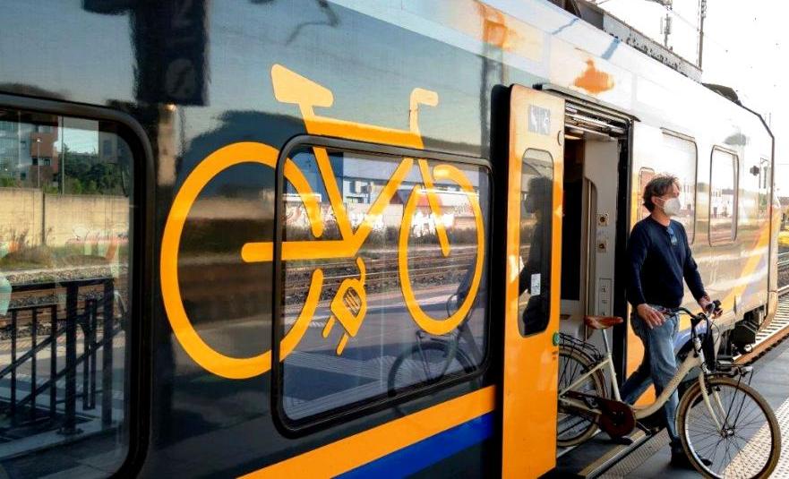 Ciclista con bici in uscita da un treno regionale