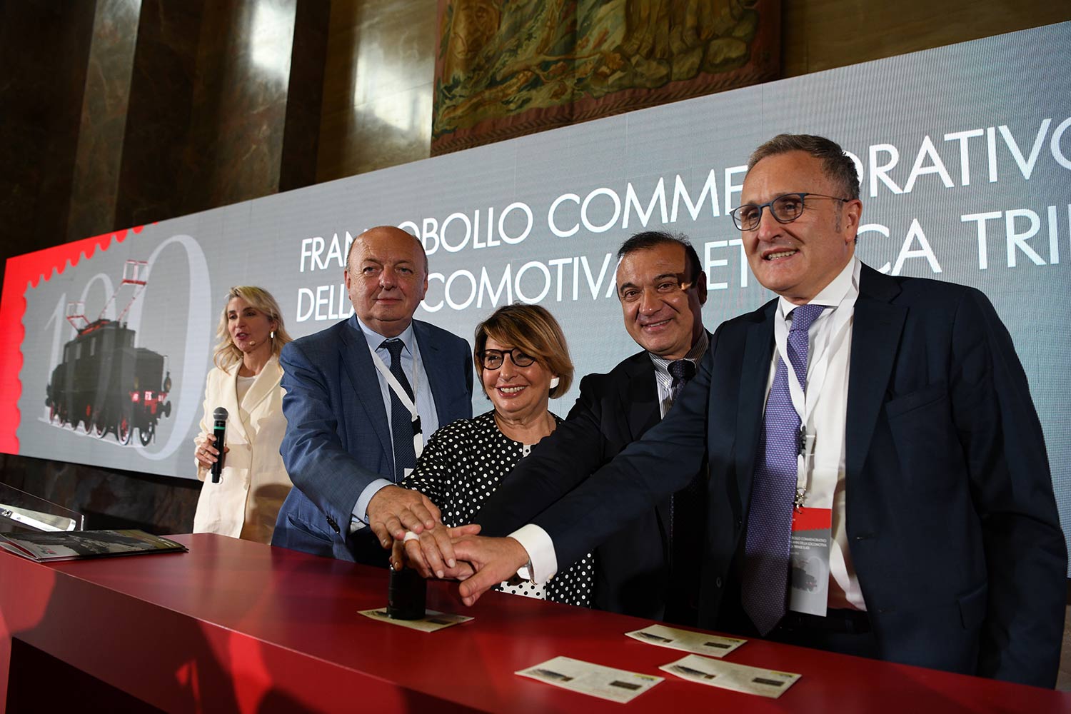 Gilberto Pichetto Fratin (Viceministro allo Sviluppo Economico), Maria Bianca Farina (Presidente di Poste Italiane), Fabio Gregori (Responsabile Filatelia di Poste Italiane) e Luca Torchia (Chief Communication Officer del Gruppo FS) per l’annullamento filatelico del francobollo commemorativo della locomotiva E.431 a 100 anni dalla costruzione
