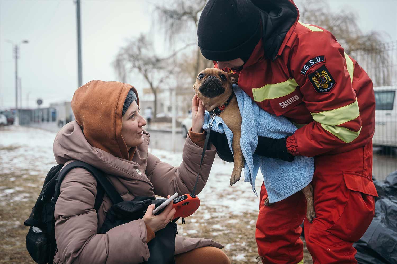 Un soccorritore si prende cura del cane di una donna ucraina in fuga, dopo il superamento del confine verso Siret, in Romania
