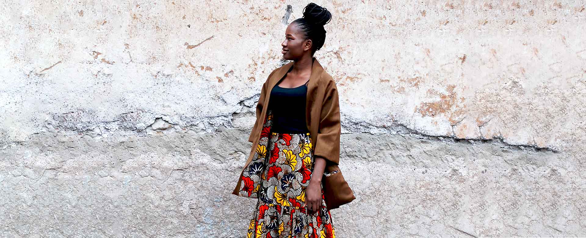Sayon Diarra, sarta artigiana migrante del Mali, indossa una maxi skirt e un kimono double-face della collezione Fall-Winter 22, creati con lana italiana e tessuto wax africano