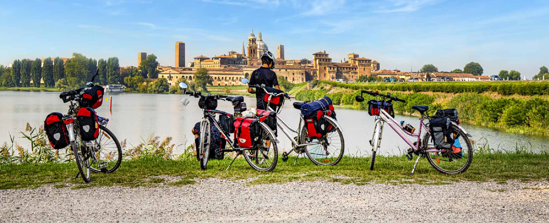 Ciclista in riva al fiume di fronte al centro di Mantova